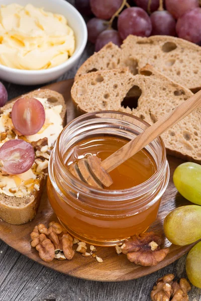 flavored honey, bread with butter and grape on wooden board