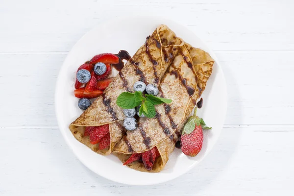 Crepes with berries and chocolate sauce, top view — Stock Photo, Image
