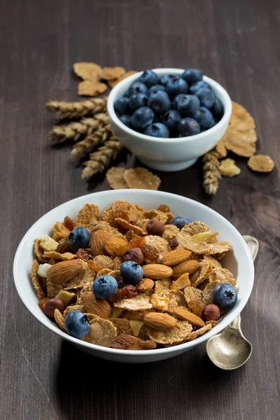 Cereal flakes with blueberries and nuts on a dark wooden table — Stock Photo, Image