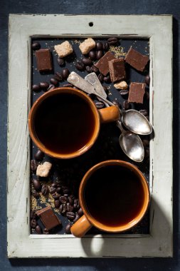 İki fincan sade kahve, şeker ve çikolata bir kara tahta üzerinde