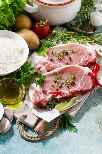 Two pieces of pork on a cutting board and fresh foods — Stock Photo, Image