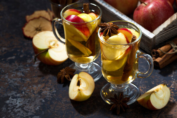 glasses of hot apple tea with spices on dark table, horizontal
