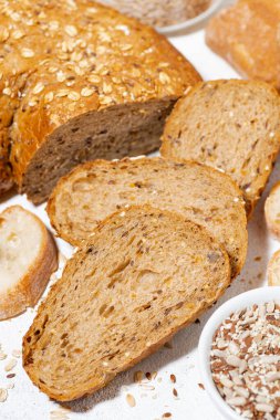 Yulaf ve çekirdekli çeşitli taze ekmekler dilimlere ayrılmış, dikey.