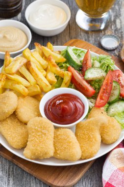 lunch with chicken nuggets, french fries, fresh salad and beer, closeup