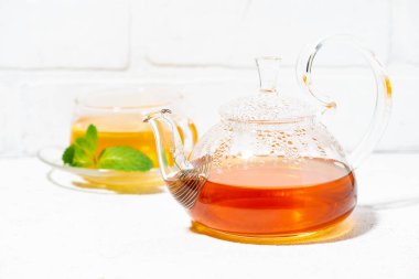 Beyaz zemin üzerindeki bağışıklığı arttırmak için limonlu, zencefilli ve naneli çay demliği.