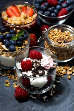 Koyu arkaplanda böğürtlen ve kremalı çeşitli tatlılar, dikey, üst görünüm