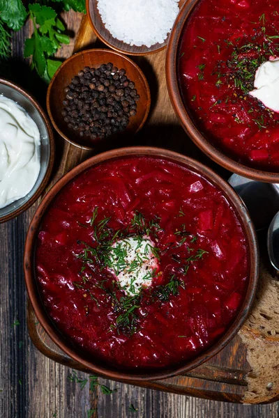 traditional russian dish borsch with sour cream and dill on wooden background, top view