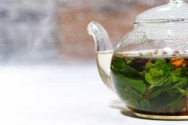 Beyaz arka planda taze naneli ve limonlu cam çaydanlık çayı, yakın plan.