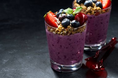 Koyu arkaplanda granola ve böğürtlenli sağlıklı tatlı, yakın plan, yatay