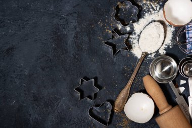 Siyah arkaplanda pişirmek için un, form ve malzeme içeren kaşık, üst görünüm yakın plan.