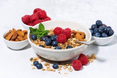 Sağlıklı kahvaltı. Tahıl gevreği, taze böğürtlen ve meyveler beyaz masada, yakın çekim yatay