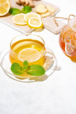 Beyaz arka planda bağışıklığı arttırmak için limonlu, zencefilli ve naneli bir fincan sıcak çay.