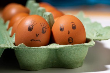 Beyaz arkaplanda boyalı yüzleri olan tavuk yumurtalı kutu, yatay yakın plan