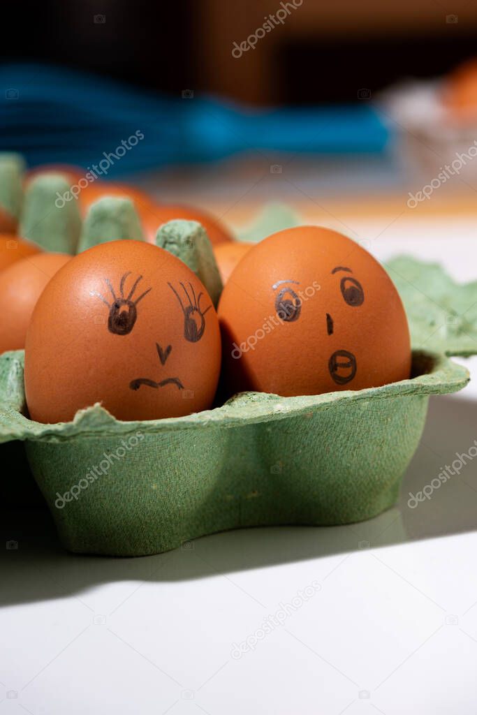 box with chicken eggs with painted faces on white background, closeup