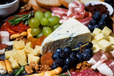 Çeşitli peynirler, taze meyve ve etler, yakın plan.