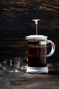 Koyu arka planda çay ve kahve demlemek için boş Fransız presi, dikey yakın plan