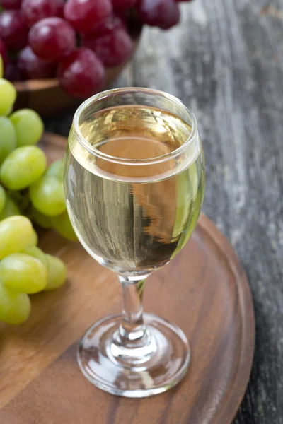 Glas Weißwein und Trauben auf einem Holzbrett, Draufsicht — Stockfoto