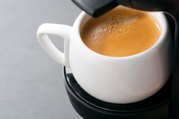 Weiße Tasse Kaffee in der Kaffeemaschine, Nahaufnahme — Stockfoto
