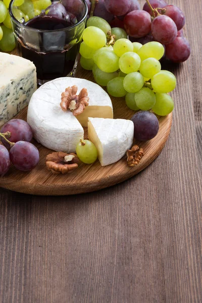 Çeşitli peynirler ve tahta üzerinde taze üzüm — Stok fotoğraf