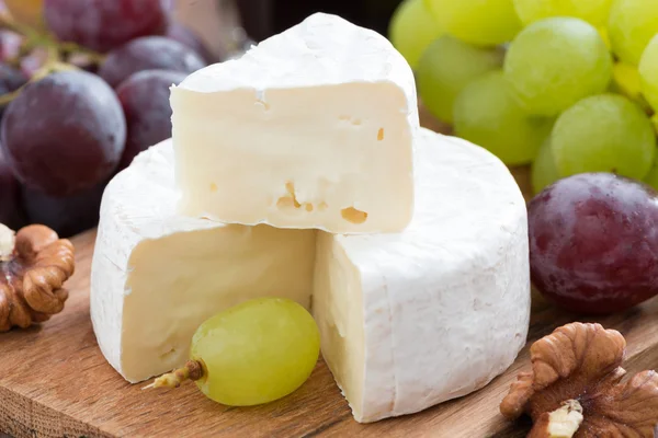 Fresh camembert on a wooden board and grapes, close-up — Stock Photo, Image