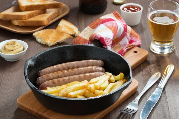 Embutidos a la parrilla con papas fritas, tostadas y cerveza — Foto de Stock