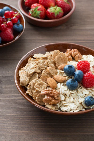 Havregryn och müsli i en skål, färska bär på trä bakgrund — Stockfoto