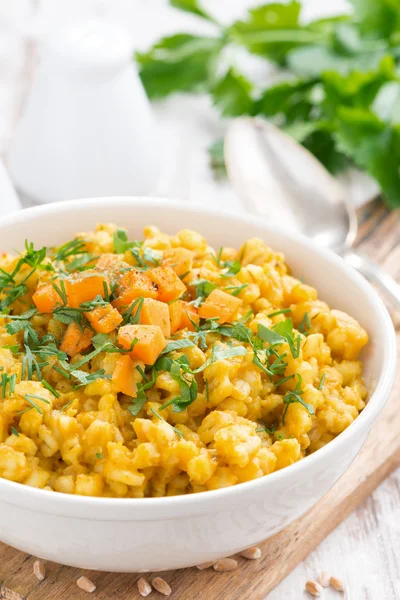 Barley porridge with pumpkin and greens in a bowl, vertical — Stock Photo, Image