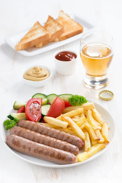 Grilled sausages with French fries, vegetables and glass of beer — Stock Photo, Image