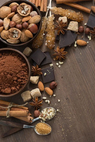 Какао, шоколад, горіхи та спеції на дерев'яному фоні, вертикально — стокове фото