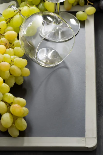 Empty wine glass and grapes on a blackboard — Stock Photo, Image