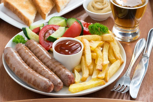 Lunch with grilled sausages, French fries, vegetables and beer — Stock Photo, Image