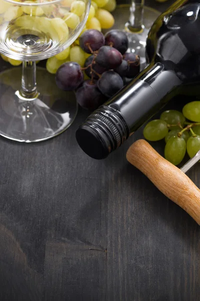 Bottle of red wine, empty glass and grapes on wooden background — Stock Photo, Image