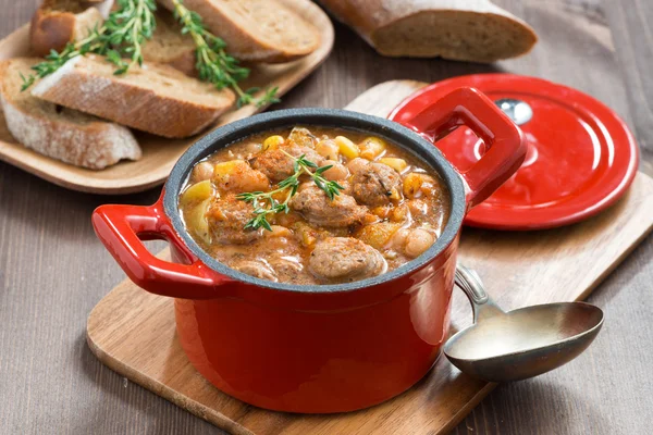 Delicious vegetable stew with sausages in a red pan — Stock Photo, Image