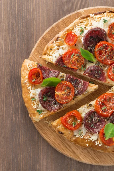 Italiaanse pizza met salami en tomaten op houten achtergrond — Stockfoto