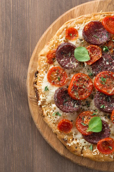 Italiensk pizza med salami och tomat på trä bakgrund — Stockfoto