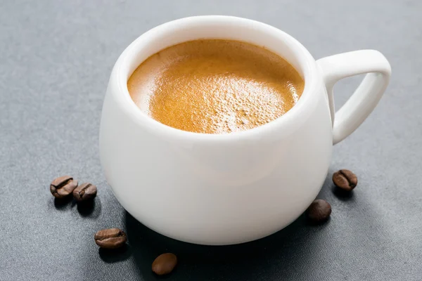 Kopp espresso på en mörk bakgrund och kaffebönor, närbild — Stockfoto