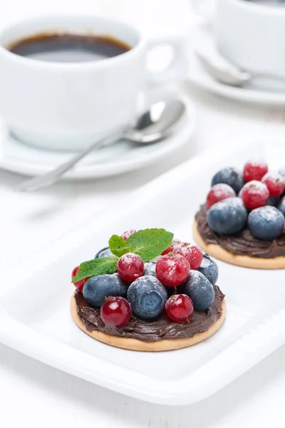 Mini cakes with chocolate cream and berries and coffee — Stock Photo, Image