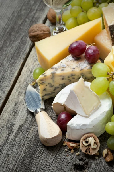 Färska ostar, druvor och valnötter på en trä bakgrund — Stockfoto