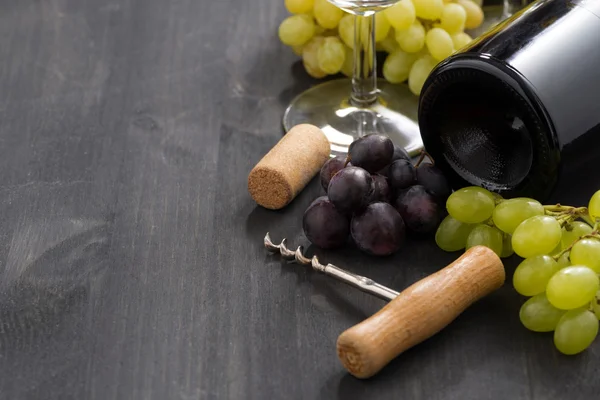Fles rode wijn en druiven op een houten achtergrond — Stockfoto