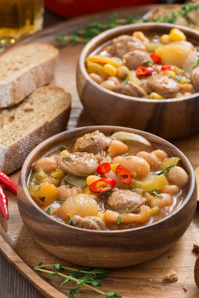 Vegetable stew with sausages in a wooden bowl, vertical — Stock Photo, Image