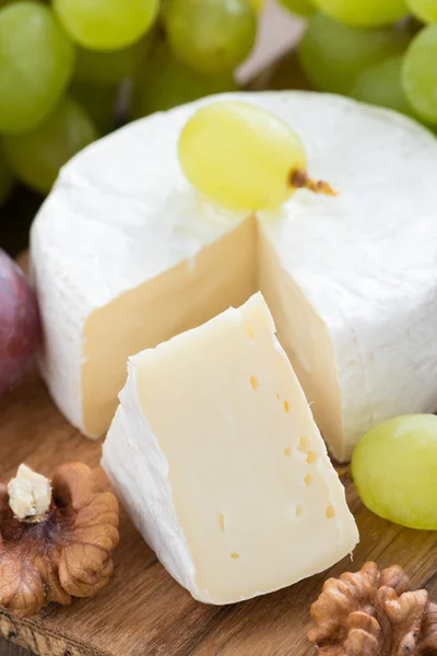 Camembert and fresh green grapes, vertical — Stock Photo, Image