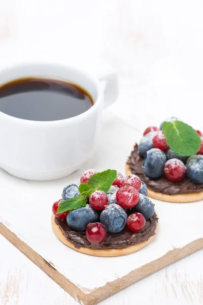 Mini pasteles con crema de chocolate y bayas y una taza de café —  Fotos de Stock