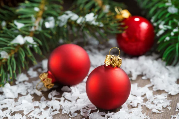 Rote Weihnachtskugeln im Schnee und Fichtenzweige lizenzfreie Stockfotos