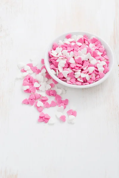Corações de açúcar coloridos em uma tigela branca na mesa de madeira branca — Fotografia de Stock