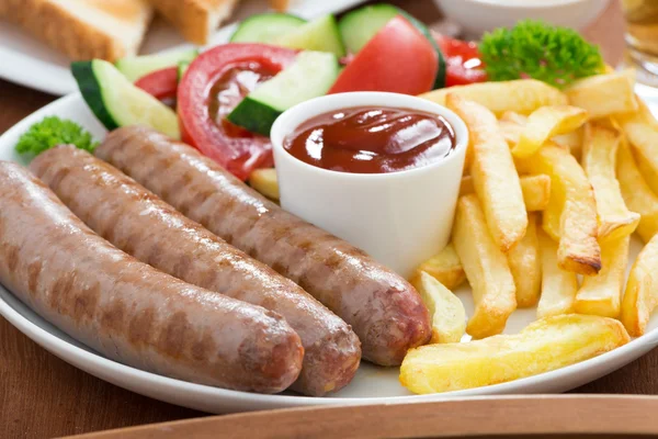 Lunch with grilled sausages, French fries, vegetables and beer — Stock Photo, Image