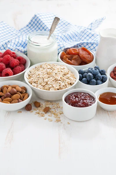 Havre flingor och olika ingredienser för frukost på vit — Stockfoto