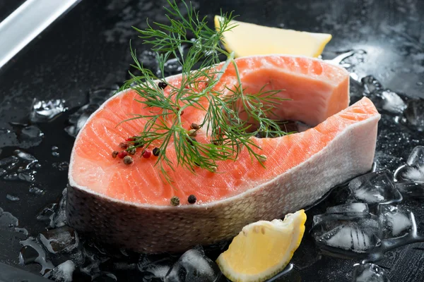 Raw salmon steak with dill and lemon on ice — Stock Photo, Image