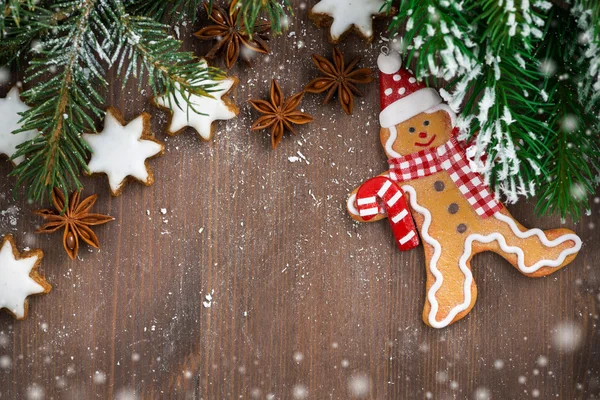 Wooden background with fir branches, cookies and gingerbread man — Stock Photo, Image