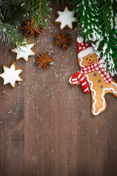 Holzhintergrund mit Tannenzweigen, Plätzchen und Lebkuchenmann — Stockfoto