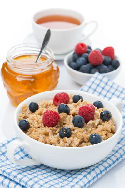 Oat porridge with berries and honey, a cup of black tea — Stock Photo, Image